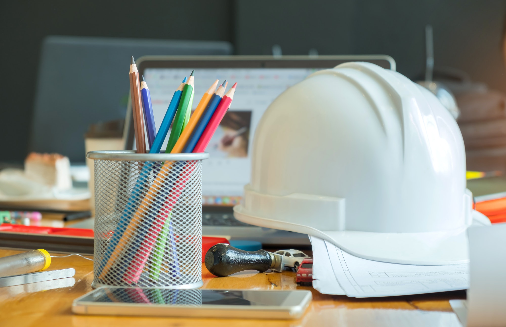 Multi colored pencils in box with safety helmet,smart phone.